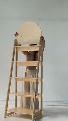 a person standing on top of a ladder holding up a wooden object to the ceiling