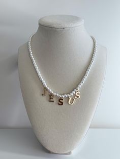 Our 16-inch faith-based necklace is a stunning expression of devotion and style. Crafted with elegant acrylic pearls and durable gold stainless steel, this piece is both timeless and meaningful. The highlight of the design is its pendants that spell out 'JESUS' in bold, gold stainless steel letters, making it a beautiful statement of faith. Perfect for daily wear or special occasions, this necklace is a graceful way to showcase your spiritual journey. Faith Based Jewelry, Jesus Necklace, Cool Necklace, Statement Of Faith, Faith Cross, Necklace Cross, Pearl Jewelry Necklace, Christian Jewelry, Cute Necklace