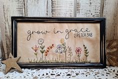 a cross - stitch frame with flowers and the words grow in grace on it next to a star