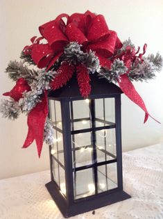 a lighted lantern with red and silver poinsettia in it on a table