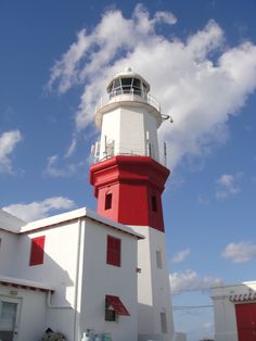 a red and white light house sitting on top of a building under a blue sky