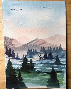 a watercolor painting of mountains and trees with birds flying over them on a wooden surface