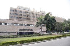 a large building with trees in front of it and a car on the road next to it