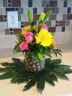 a pineapple vase filled with flowers on top of a counter next to a light switch