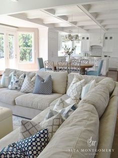 a living room filled with white furniture and lots of pillows on top of it's couches