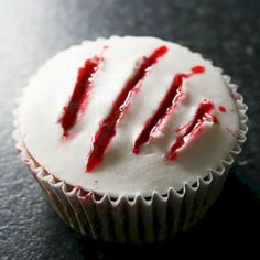 a cupcake with white frosting and red sprinkles sitting on a table