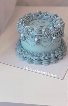 a blue frosted cake sitting on top of a white table