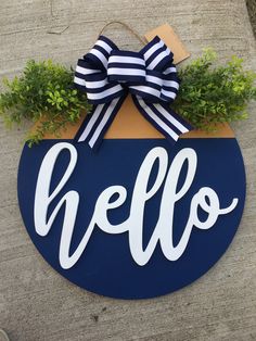 a blue and white sign that says hello hanging from the side of a building with a bow on it