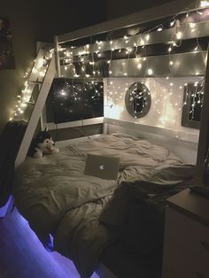 a bed room with a laptop on top of it and lights strung from the ceiling