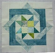 a blue and green patchwork quilt on the side of a wall