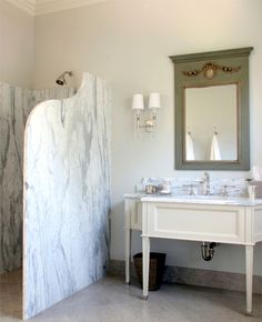 a bathroom with a marble shower stall and white sink counter top next to a mirror on the wall