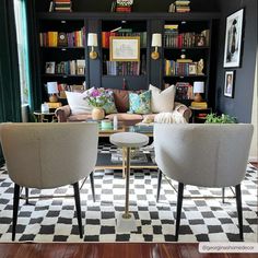 two chairs and a table in a room with bookshelves on the wall behind them