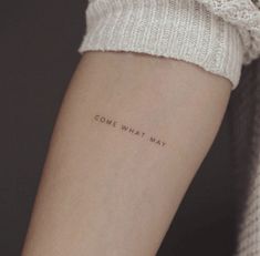 a woman's arm with the words, come what may written on it in cursive font