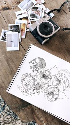 a table topped with pictures and a camera next to a drawing on top of a wooden floor