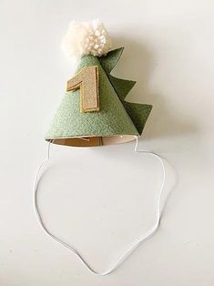 a small green christmas tree hat on top of a white wall