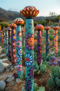 there are many colorful flowers painted on the poles in the field with rocks and succulents