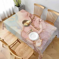 a dining room table covered in pink and gold marbled paper with white plates on it