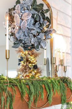 a christmas mantle decorated with greenery, candles and a wreath on top of it