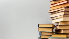 a stack of books sitting on top of each other in front of a white wall