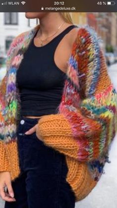 a woman standing in the snow wearing a colorful cardigan