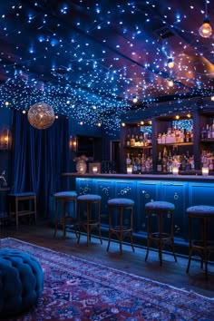 a dimly lit bar with stools and lights on the ceiling, in front of blue curtains