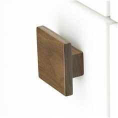 a close up of a wooden door handle on a white wall with wood grained finish