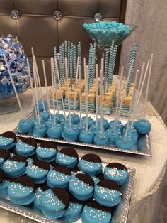 blue desserts and cupcakes are displayed on silver trays at a party