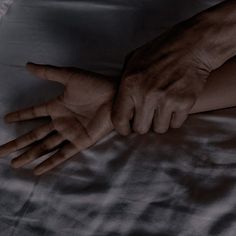 two hands reaching for each other on a bed