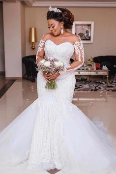 a woman in a wedding dress holding flowers and posing for the camera with her hands on her hips