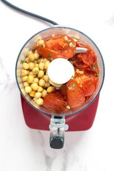 a food processor filled with tomatoes and chickpeas