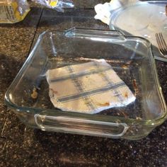 a glass dish with some food in it on a counter top next to a knife and fork