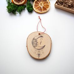 an ornament is hanging on a piece of wood with oranges and herbs around it