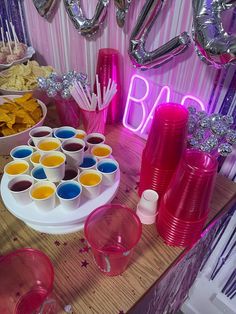 a table topped with plates and cups filled with food next to balloons in the shape of letters