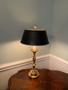 a lamp sitting on top of a wooden table next to a white wall and blue walls