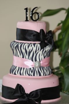 a pink and black cake with zebra print on it's side, decorated with a bow