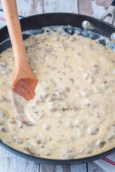 a wooden spoon in a skillet filled with cheese gravy on top of a table