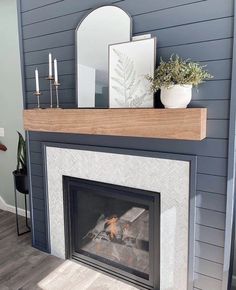 a fireplace with a mirror and candles on it's mantle, in front of a blue wall