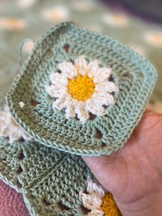 two crocheted grannys are being held by someone's hand