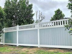 a large white fence sitting next to a lush green field