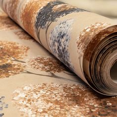 a roll of brown and white wallpaper with trees on it's side, laying on top of the floor