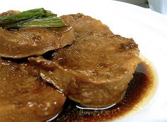 a white plate topped with meat covered in gravy