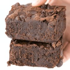 two pieces of chocolate brownies being held by someone's hand with their fingers