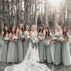 a group of women standing next to each other in front of some trees and grass