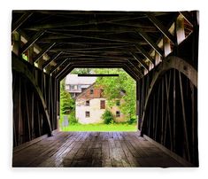 an old wooden bridge with a house in the background and trees on both sides that are overhanging