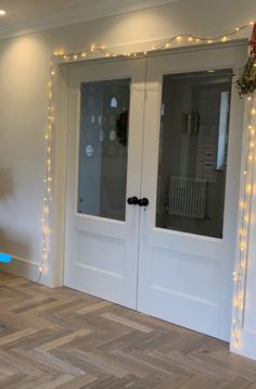 an empty room with some lights on the wall and two glass doors that are open