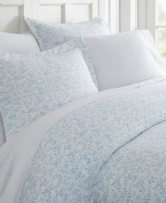 a bed with white sheets and blue pillows