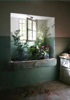 an old bathtub with flowers in it next to a sink and window sill