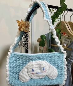 a crocheted purse hanging on a rack in a room with clothes and other items