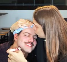 a man and woman kissing each other while they are brushing their teeth