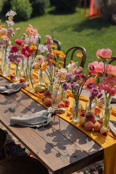 a long table with many vases filled with flowers on top of it, along with plates and utensils